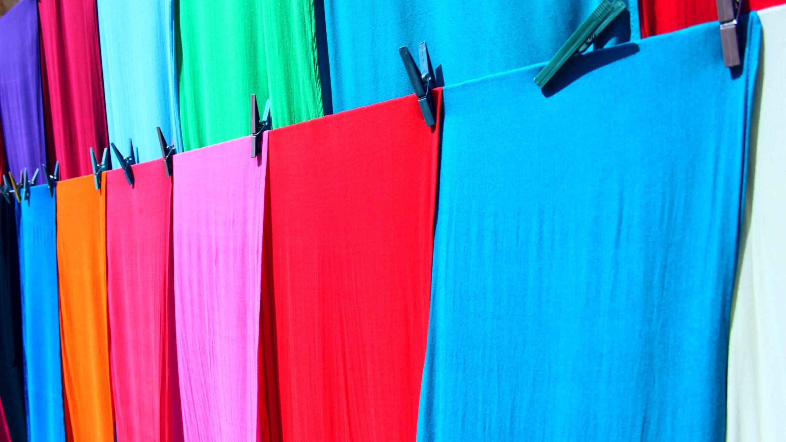 Different colour materials hung up on a clothes line 