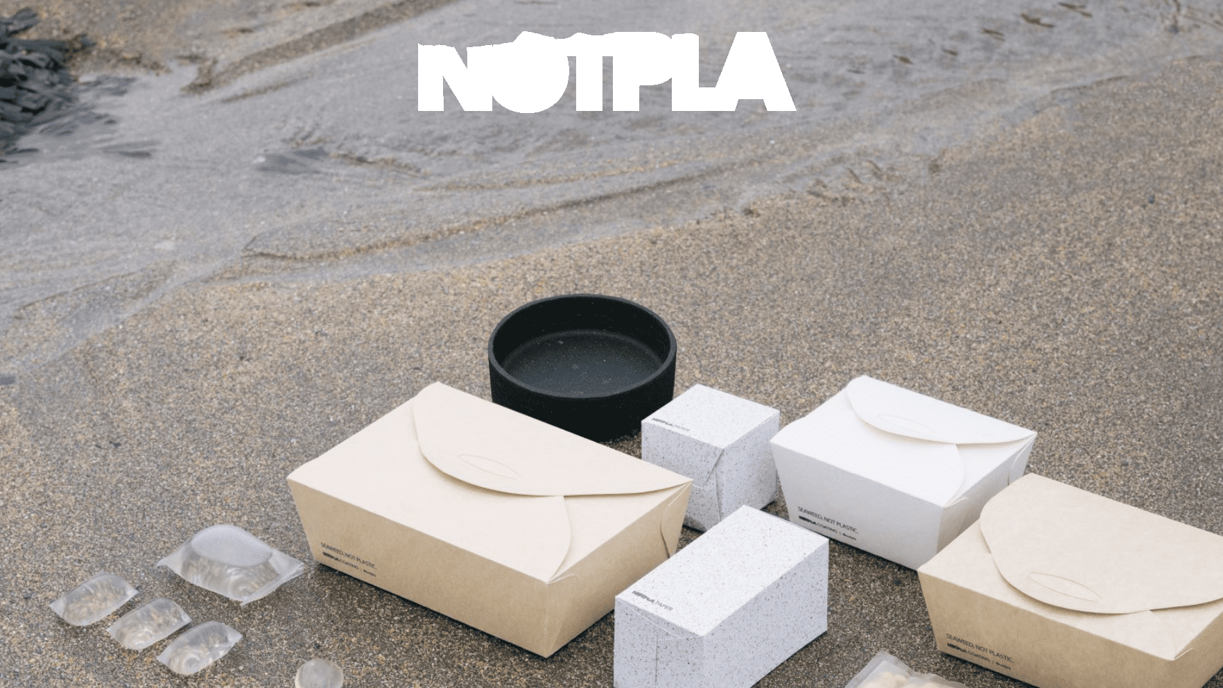 All products of Notpla laid out on the beach.